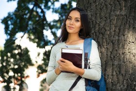 تصویر عکس با کیفیت با کتاب توی دست به درخت تکیه داده 