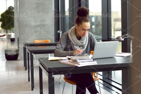 تصویر عکس با کیفیت دختر نشسته روی میز در حال تایپ 