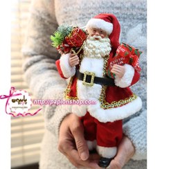 تصویر فیگور کریسمسی اروپایی بابانوئل همراه با کیسه هدایا و درخت کاج 
