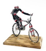تصویر مجسمه مفتولی دوچرخه‌سوار دست‌ساز روی پایه چوبی 
