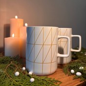 تصویر ماگ سرامیکی مینیمال سفید ، طراحی مدرن با خطوط طلایی 