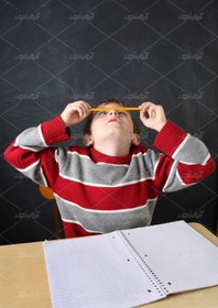 تصویر عکس با کیفیت پسربچه با دفترش روی میز 